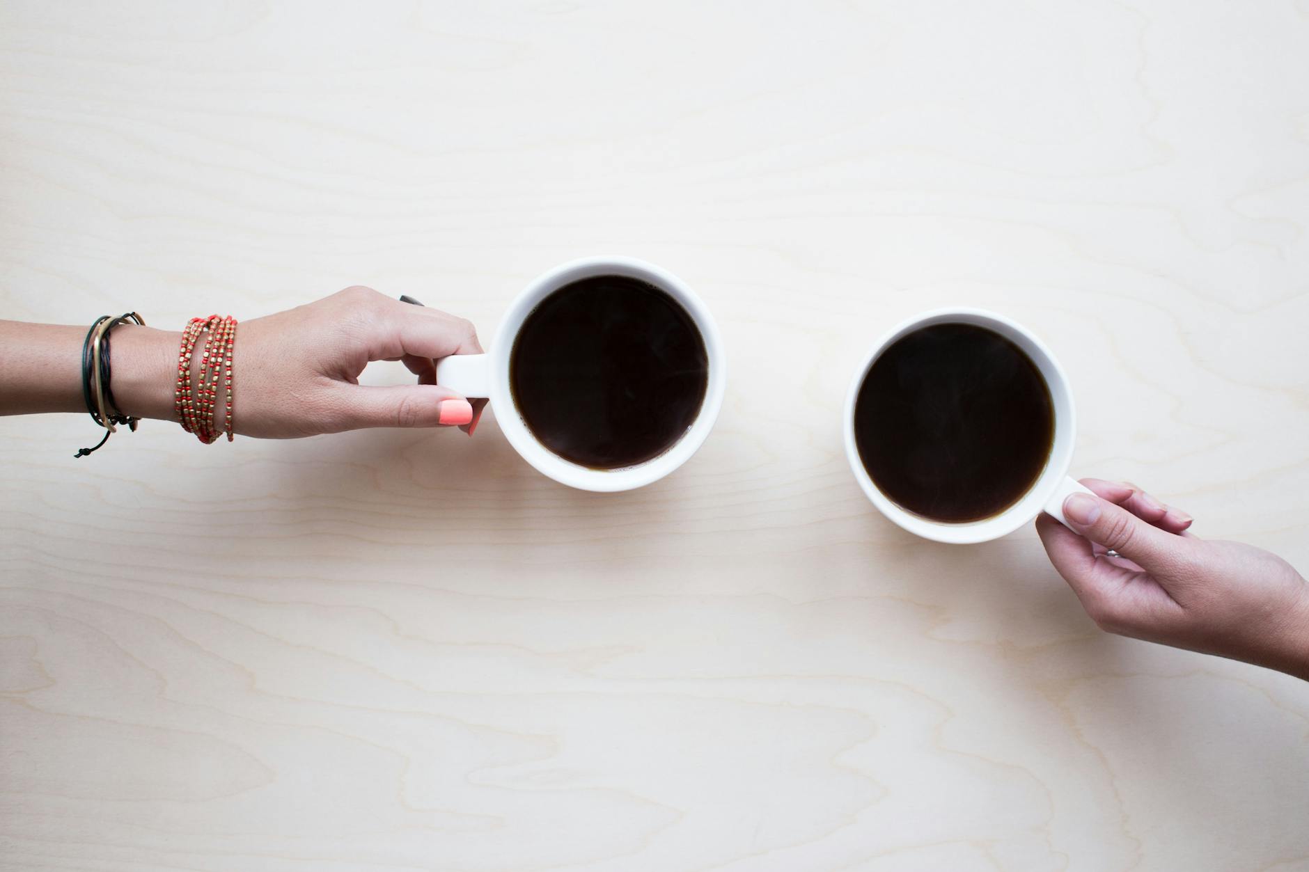 person holding white ceramic mug with black liquid
